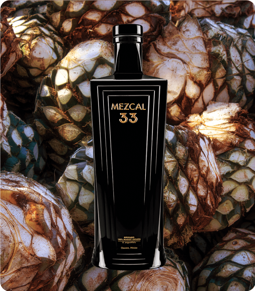 Mezcal 33 Reposado — botella sobre piñas de agave